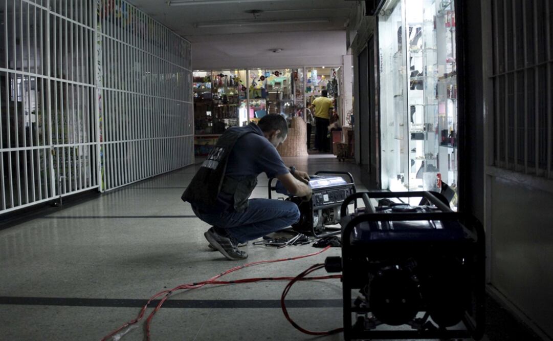 Un hombre enciende un generador eléctrico para mantener las luces encendidas de los locales de un centro comercial en Tachira, Venezuela (Foto: Reuters)