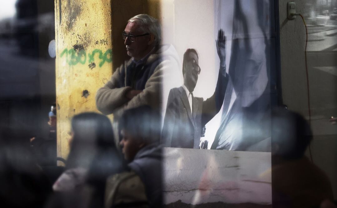 Fotografía de una imagen del ex presidente Salvador Allende reflejada en un vidrio entre personas que visitan el museo de memoria en el Estadio Nacional, el 26 de agosto 2023, en Santiago (Chile). Foto: EFE