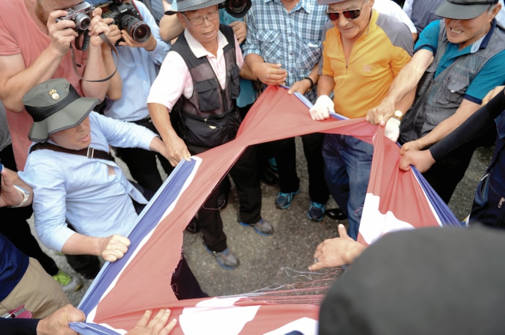 Surcoreanos muestran una bandera de Corea del Norte, donde está pintada la palabra “pu ñ a l ad a”, durante una protesta contra el régimen comunista, en el puente de la Unificación, que conduce a la Zona Desmilitarizada (AP)