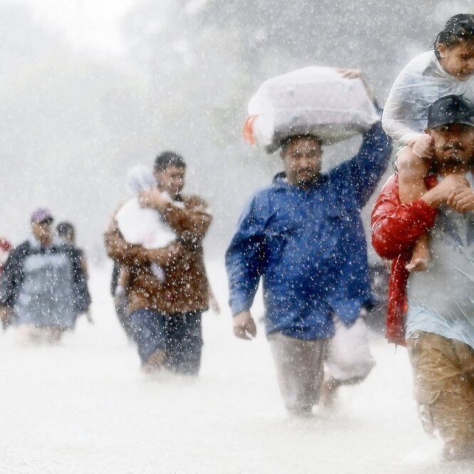 Lugareños caminan bajo la lluvia de una tormenta tropical, en Houston. Sequías e inundaciones serán más frecuentes por el calentamiento global. ARCHIVO. REUTERS