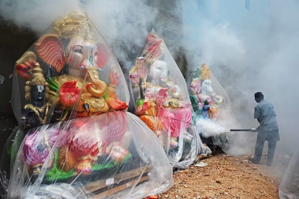 Un trabajador municipal fumiga una colonia de viviendas y estatuas de la deidad hindú con cabeza de elefante Ganesha antes del festival Ganesh Chaturthi en Chennai el 13 de septiembre de 2023. FOTO:  R. SATISH BABU - AFP