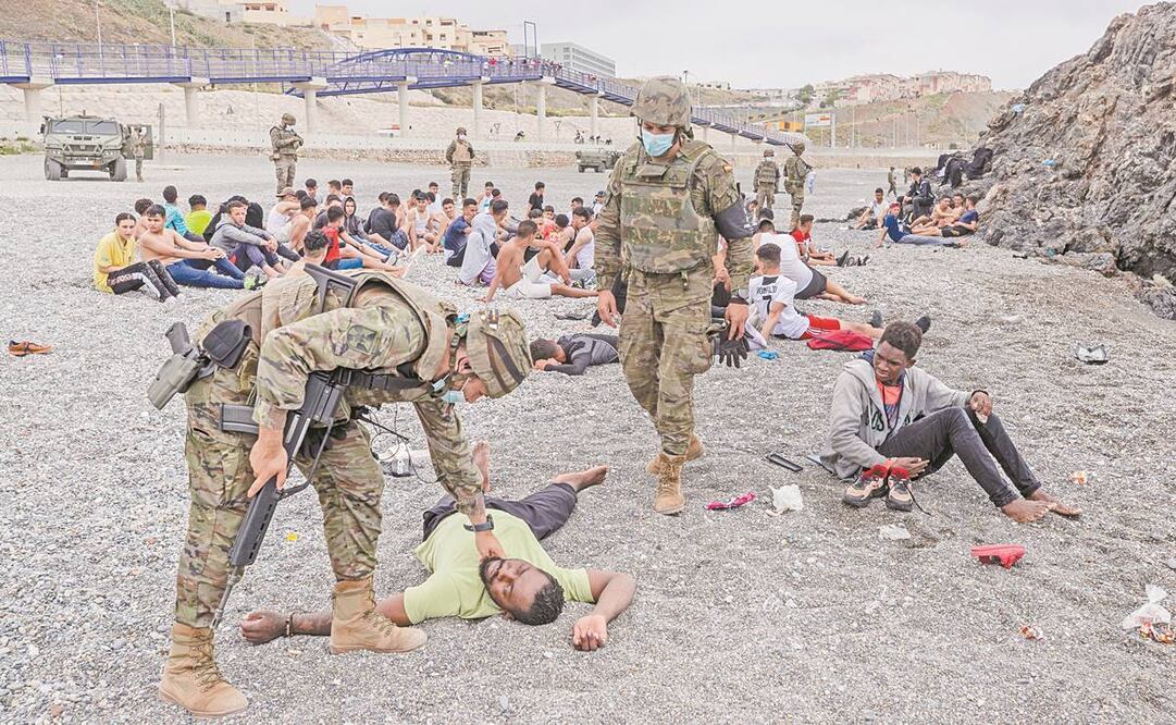 Un migrante es asistido por soldados del Ejército español cerca de la frontera de Marruecos y España, en el enclave español de Ceuta, el 18 de mayo pasado. Foto: Bernat Armangue/ AP.