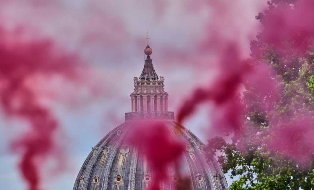 Una columna de humo rosa se eleva frente a la Cúpula de San Pedro durante una protesta de la Conferencia de Ordenación de Mujeres, que exige la plena igualdad de las mujeres en la Iglesia Católica, el primer día del cónclave para elegir al 267.º papa, en Roma, el miércoles 7 de mayo de 2025. Foto: AP