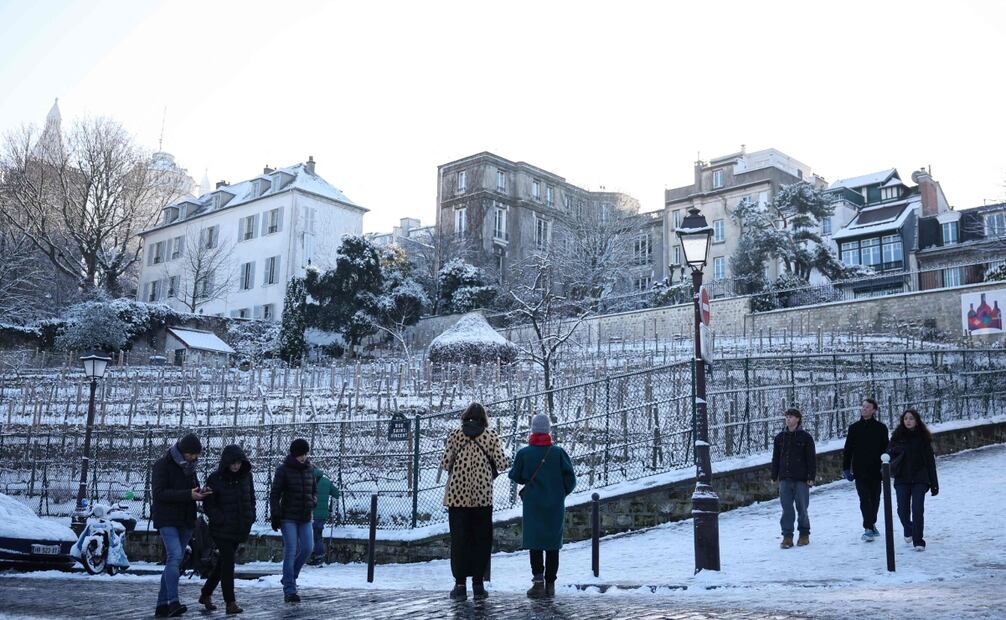 Los peatones caminan por una acera cubierta de nieve junto a los viñedos de Montmartre en París el 6 de enero de 2026. Foto: AFP