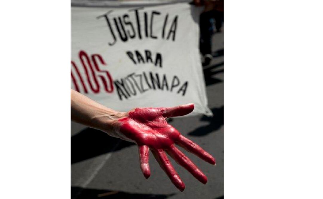 A woman shows a hand painted red in front of a banner that says: "Justice for Ayotzinapa" during a march of relatives of the 43 missing students in Mexico City on June 26. (Photo: AP)