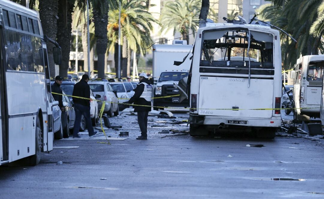 Policías forenses tunecinos inspeccionan los restos de un autobús tras el atentado contra varios guardias presidenciales que viajaban en el vehículo. Foto EFE