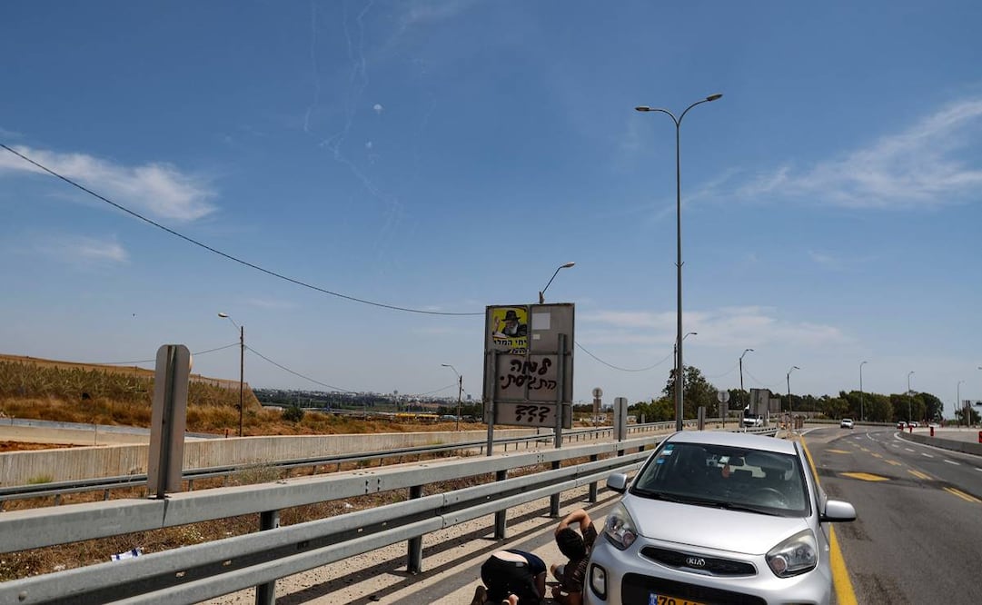 La gente se cubre mientras los misiles del sistema de defensa aérea Cúpula de Hierro de Israel interceptan cohetes disparados por el grupo Hamas. FOTO: AFP