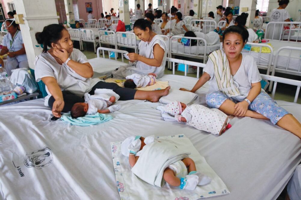 Mamás y sus bebés comparten camas en el hospital Fabella de Manila, donde un ministro ha pedido a las mujeres posponer sus embarazos debido al zika (ROMEO RANOCO. REUTERS)