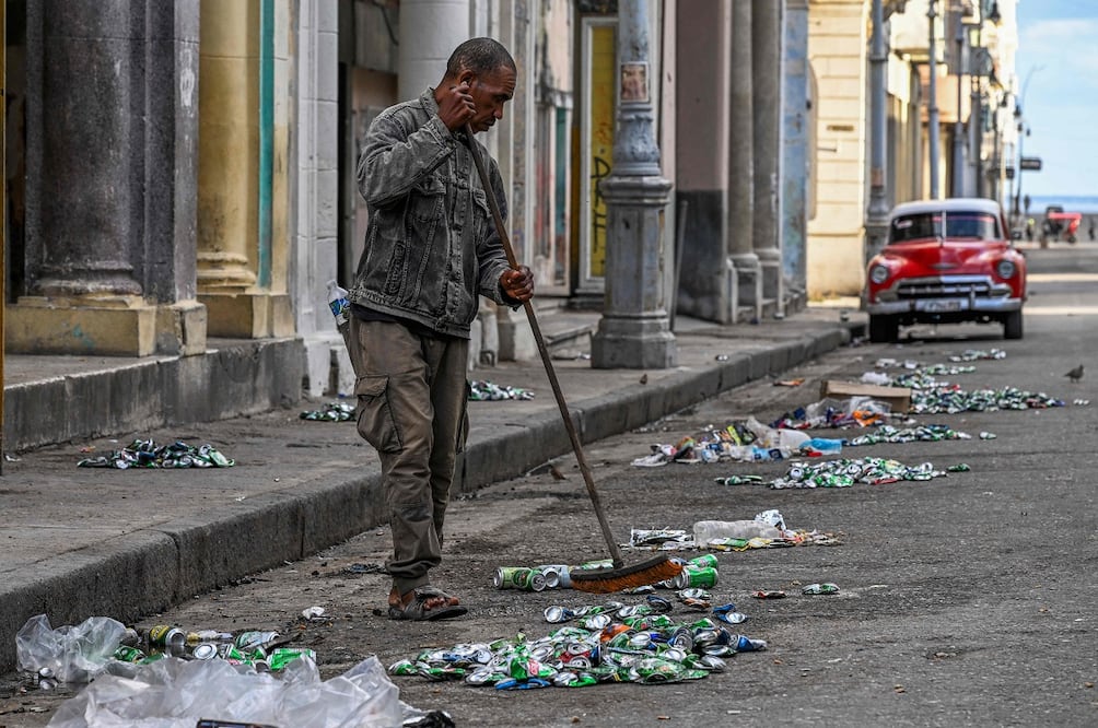 Un  hombre barre la calle, en medio de un apagón nacional en La Habana. FOTO: YAMIL LAGE. AFP