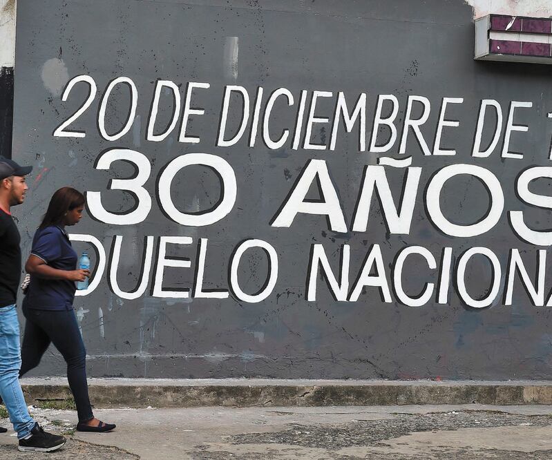 Panameños caminan al lado de un mural que conmemora los 30 años de la invasión estadounidense, en Ciudad de Panamá. LUIS ACOSTA. AFP