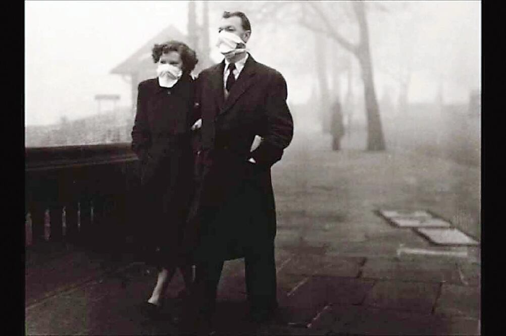 Una pareja, con tapabocas, camina por las calles de Londres, bajo una densa nube tóxica, en esta imagen de 1952 (TOMADA DE YOUTUBE)