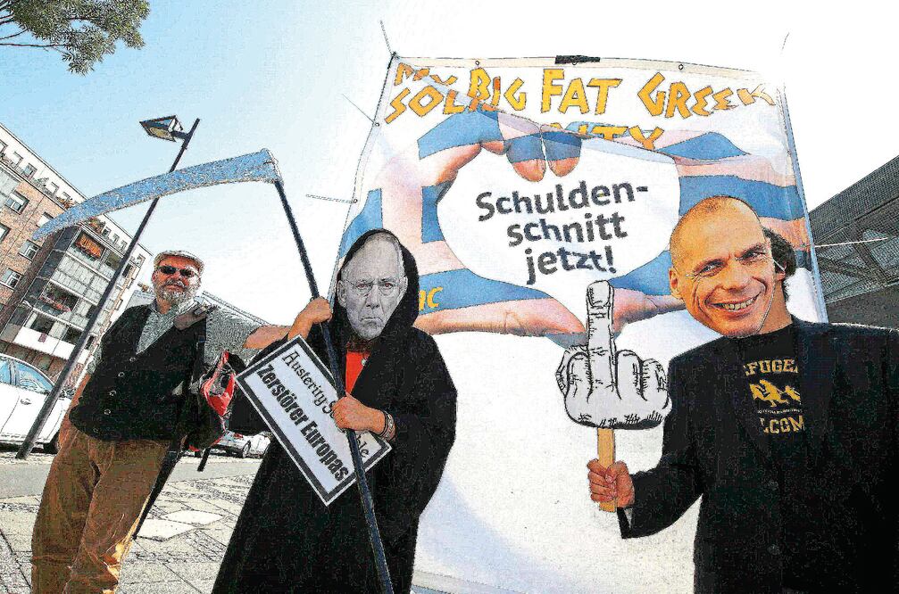Manifestantes con las máscaras del ministro alemán de Finanzas, Wolfgang Schäuble (izq.) y el ex ministro griego de la misma cartera, Yanis Varoufakis, durante una protesta afuera de la sede del Banco Central Europeo, en Frankfurt, ayer (REUTERS)