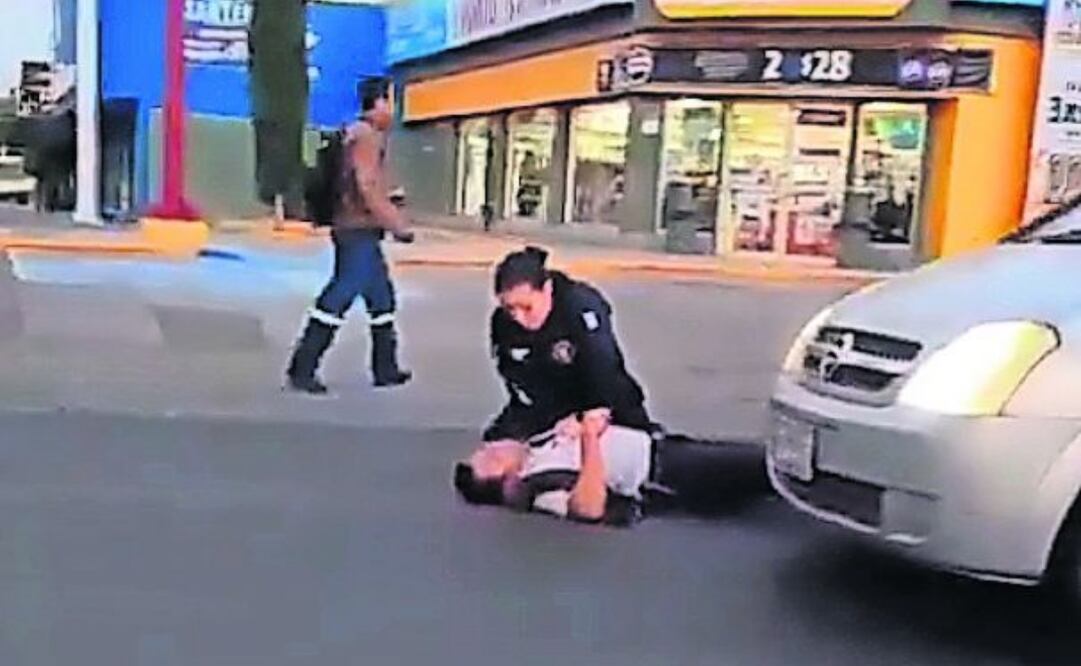 Una mujer policía trata de reanimar a su compañero baleado por dos civiles armados; el elemento murió en el hospital. Foto: Especial