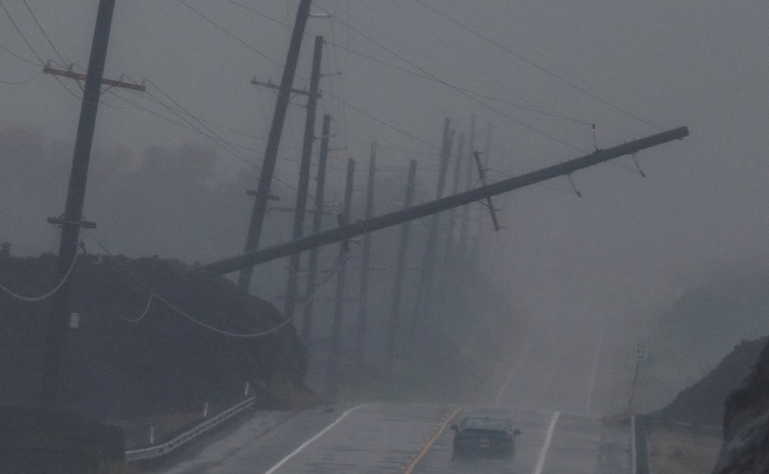 Un vehículo circula cerca de un poste de tendido eléctrico derribado que cuelga sobre la autopista Mamalahoa durante el huracán Lala, cerca de Ocean View, Hawái, el sábado 15 de agosto de 2026. Foto: AP