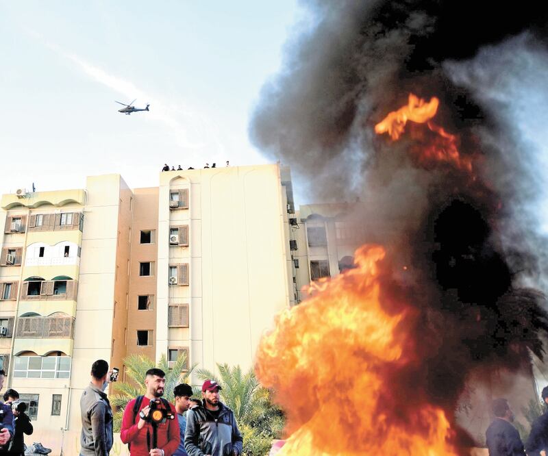 Un helicóptero estadounidense Apache AH-64E vuela mientras miembros del grupo armado chiíta iraquí Fuerzas de Movilización Popular y sus partidarios prendieron fuego fuera de la embajada de Estados Unidos. Foto: MURTAJA LATEEF. EFE