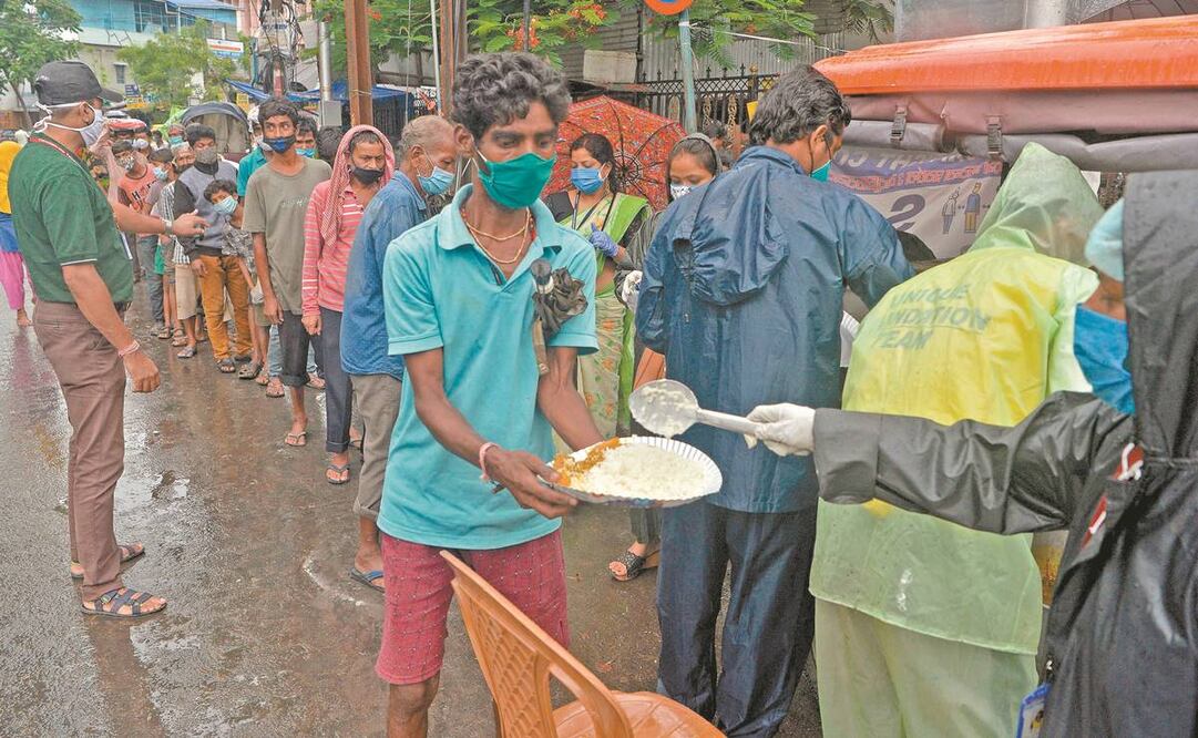 Personas que en su mayoría están sin trabajo debido a un bloqueo parcial y restricciones de viaje impuestas para frenar la propagación del coronavirus reciben comida de voluntarios en Siliguri, India, el 28 de mayo pasado. Foto: Diptendu Dutta/ AFP.