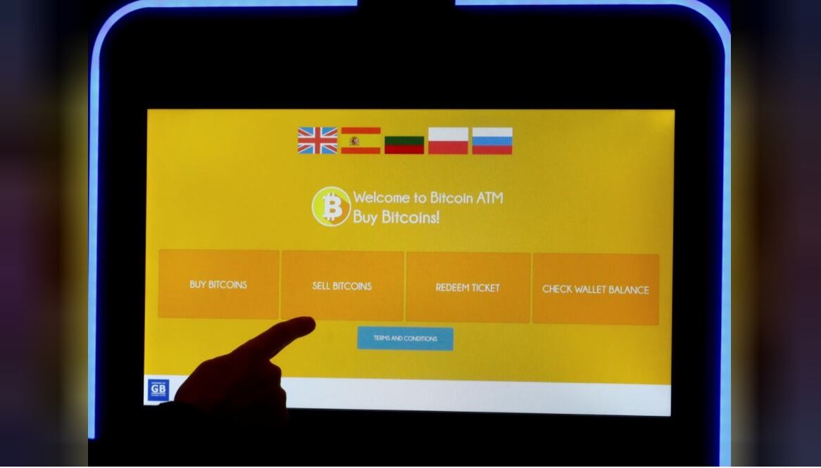 A man touches a screen of a bitcoin ATM – Photo: Ints Kalnins/REUTERS