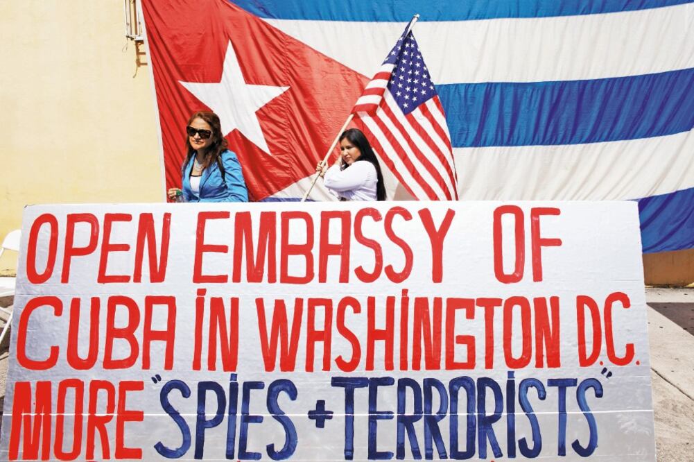 Un funcionario de la embajada de EU en La Habana pide a los transeúntes que se alejen, desde la puerta de la misión. (JAVIER GALEANO. REUTERS)