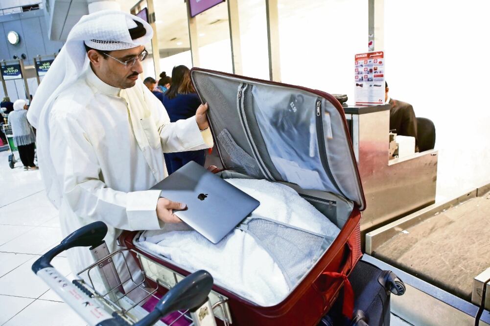 Un activista guarda su laptop en la maleta, en el Aeropuerto Internacional de Kuwait, antes de viajar a EU. Están prohibidos esos aparatos en las cabinas de los aviones (YASSER AL-ZAYYAT. AFP)
