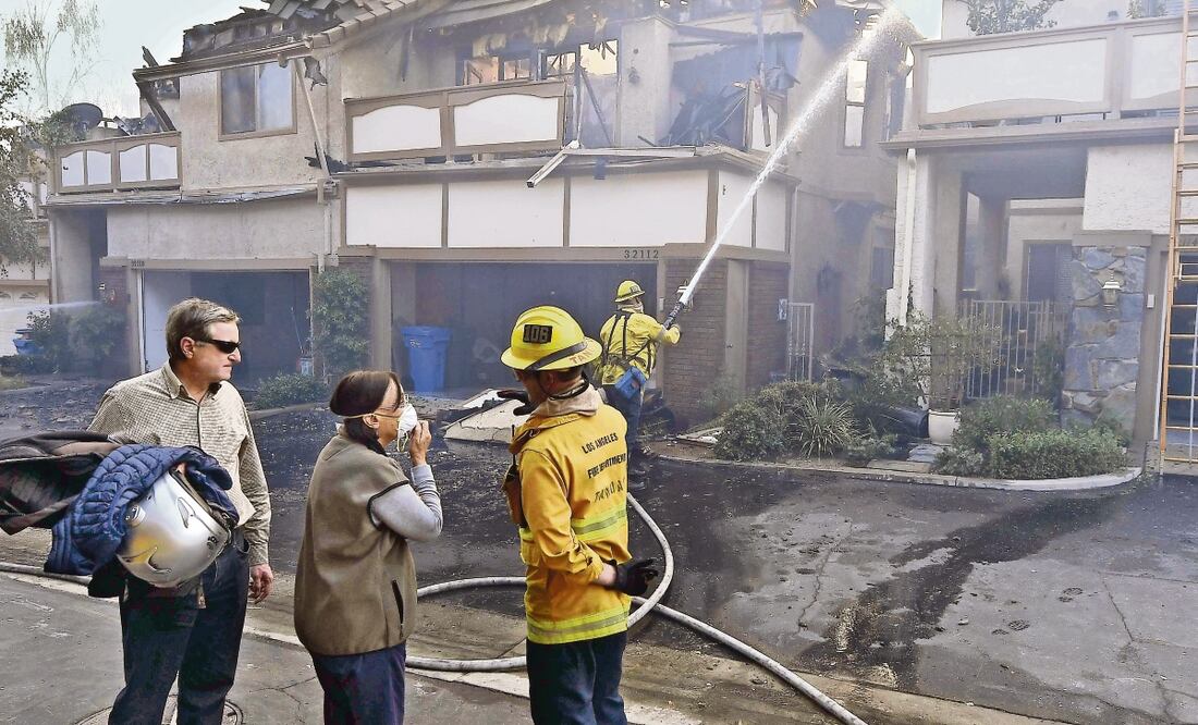 Sandro y Antoinette Zanon examinan el daño en Westlake Village, California, junto con un bombero de la ciudad de Los Ángeles, mientras las casas de sus vecinos arden por el fuego de Woolsey. (KEVORK DJANSEZIAN. AFP)