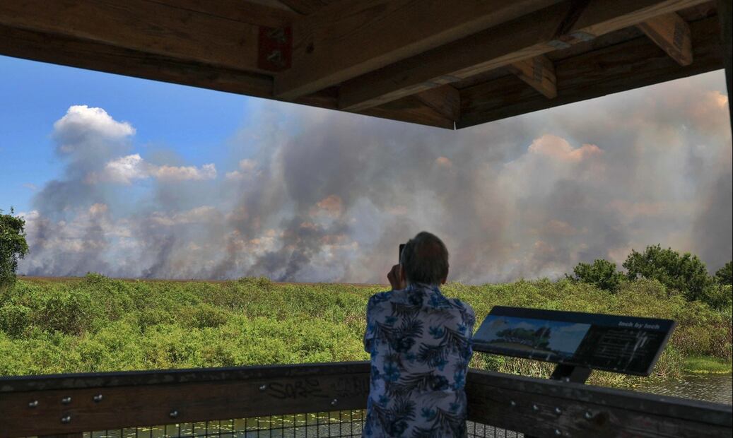 Un hombre graba con su celular las columnas de humo de un incendio forestal en los Everglades, Florida, el 20 de agosto de 2025. Foto: AFP