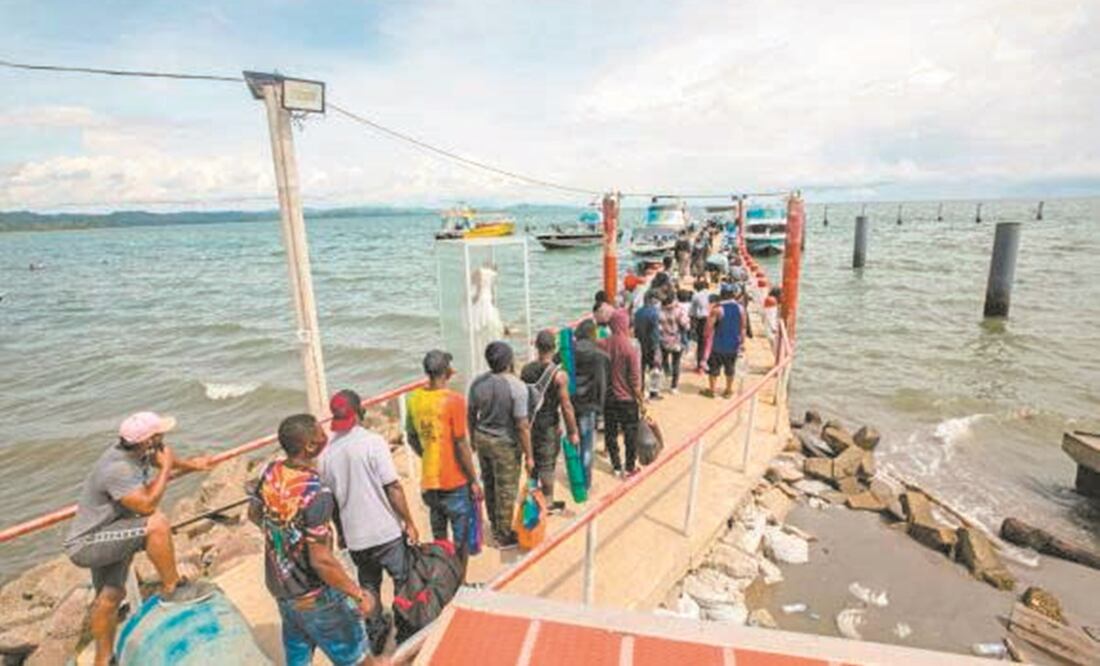 Migrantes irregulares latinoamericanos, asiáticos y africanos caminan por un muelle del norte de Colombia sobre el mar Caribe para abordar unas lanchas que los acerquen a Panamá. Foto: PERIÓDICO EL COLOMBIANO, DE MEDELLÍN