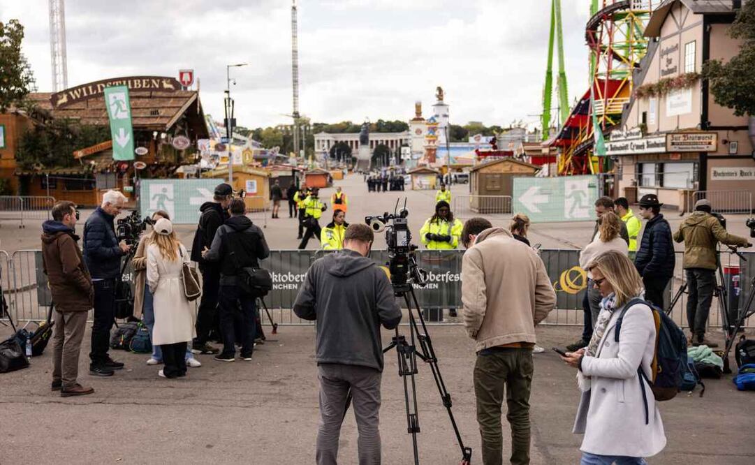 Periodistas trabajan en el recinto cerrado del Oktoberfest en Múnich, Alemania, el 1 de octubre de 2025. El recinto permanecerá cerrado hasta al menos las 17:00 h (hora local) del 1 de octubre, tras una amenaza de bomba no especificada, según informó la policía. La amenaza está relacionada con una operación policial a gran escala en el norte de Múnich, donde se encontraron artefactos explosivos dentro de una casa en llamas, dejando un muerto. Foto: EFE