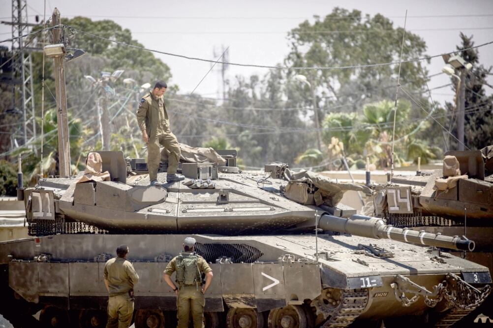 Soldados pemanecen frente a tanques israelíes dentro de una base militar cerca de la barrera con Gaza, donde el martes hubo fuertes enfrentamientos (XINHUA)