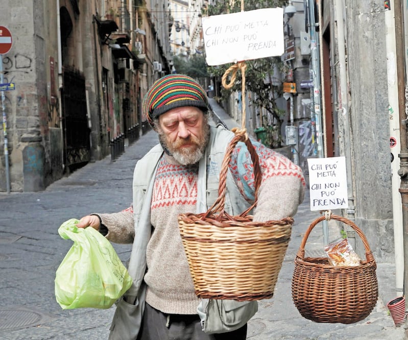 Un hombre tomó productos de una canasta de comida donada a gente de escasos recursos, en Nápoles, Italia. Foto: CIRO DE LUCA. REUTERS