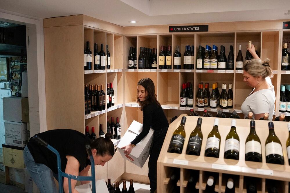 Empleados retiran vino de fabricación estadounidense de sus estanterías en Bishop's Cellar, en Halifax, Canadá. FOTO: AP