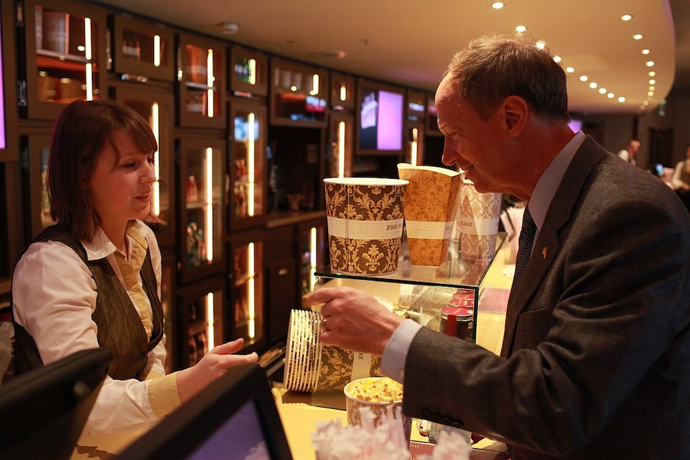 Las palomitas de maíz son una golosina clásica en las salas de cine. Actualmente hay varios tamaños de bolsas, antes todas eran iguales. En la imagen un embajador compra esta golosina. Tomada de wikimedia.