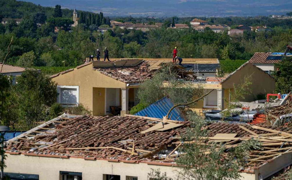 Bomberos del Grupo de Reconocimiento e Intervención en Entornos Peligrosos (GRIMP) permanecen en un tejado mientras inspeccionan un edificio dañado tras el paso de un tornado en Pomas, en el suroeste de Francia, el 25 de agosto de 2026. Foto: AFP