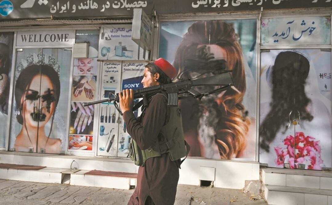 Un combatiente de los talibanes pasa frente a un salón de belleza, en Shahr-e Naw, en Kabul. Foto: Wakil Kohsar. AFP