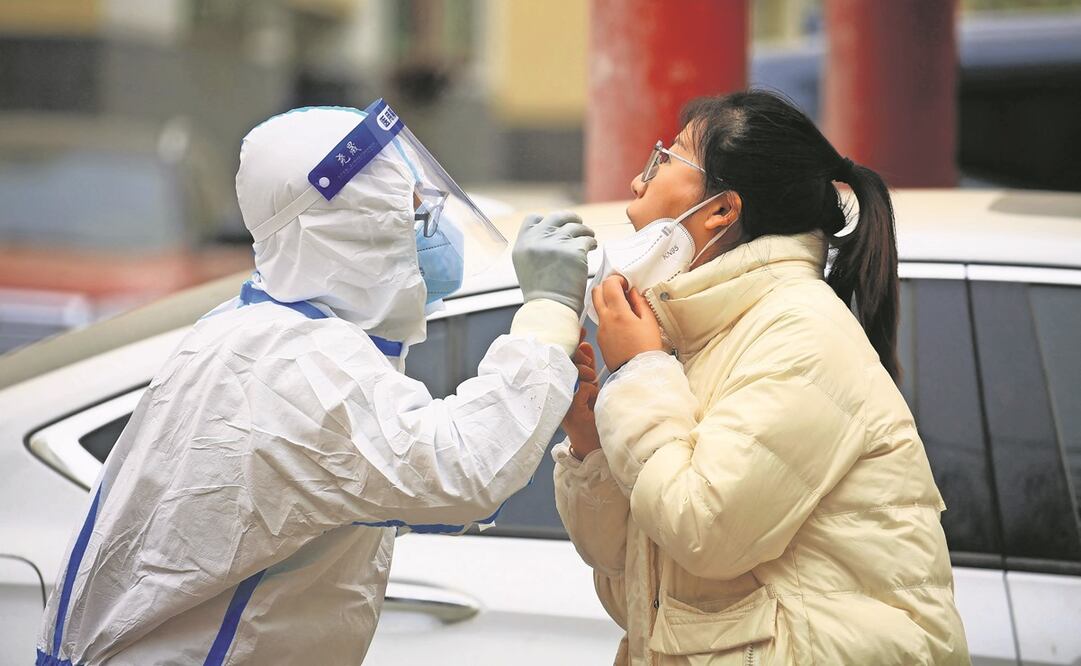 Un empleado sanitario toma una muestra de hisopo de una residente para hacerle la prueba del corona- virus, en Jiayuguan. Foto: AFP