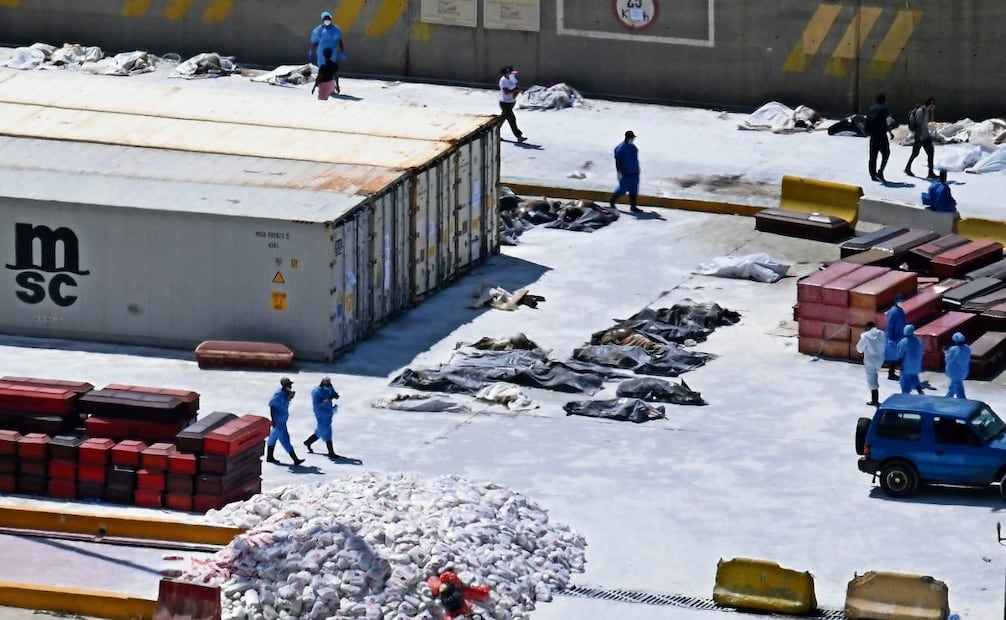 Peritos forenses alinean cadáveres en el suelo junto a ataúdes en el puerto de La Guaira. Foto: Juan BARRETO / AFP