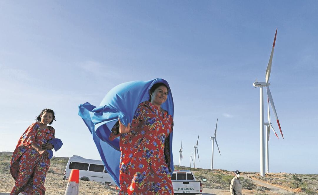 Indígenas wayús, junto a unos aerogeneradores de energía, durante la entrega del parque eólico Guajira 1, en Colombia. Foto: Mauricio Dueñas Catañeda/ EFE.