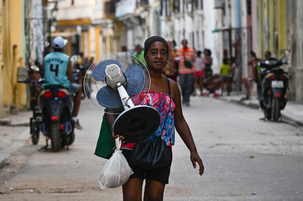 Una cubana carga un ventilador mientras camina por las calles de La Habana, en medio de un apagón nacional. FOTO: YAMIL LAGE. AFP