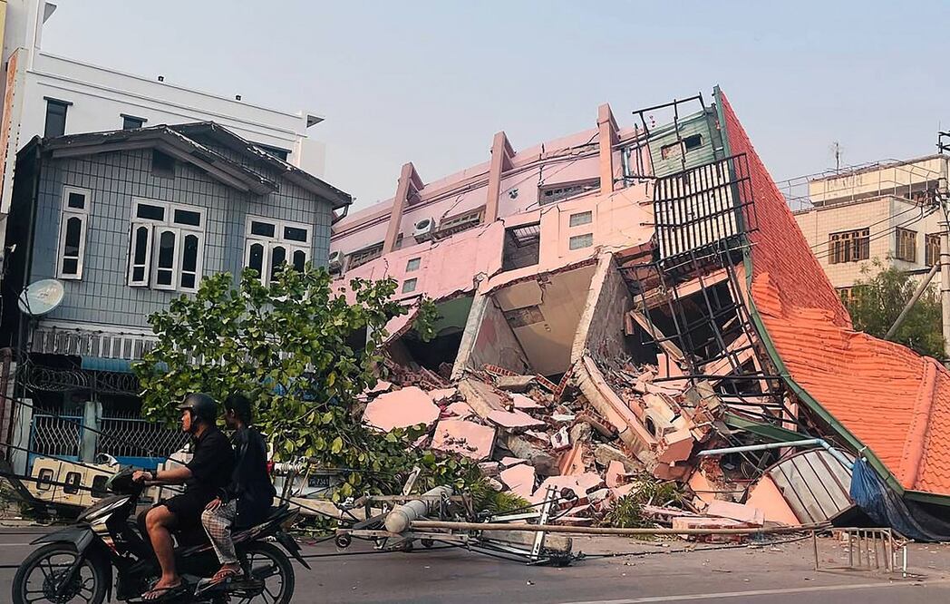 Personas en motocicleta pasan junto a un edificio derrumbado en Mandalay el 28 de marzo de 2025, tras un terremoto en el centro de Myanmar. Un potente terremoto sacudió el centro de Myanmar el 28 de marzo, deformando las carreteras de la capital, Naipyidó, dañando edificios y obligando a la gente a huir a las calles en la vecina Tailandia.  Foto: AFP