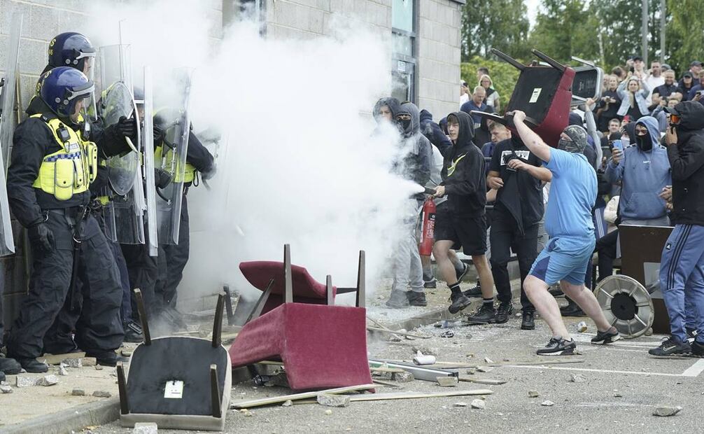 Un manifestante usa un extintor contra agentes de policía mientras estallan problemas durante una protesta contra la inmigración. FOTO: AP