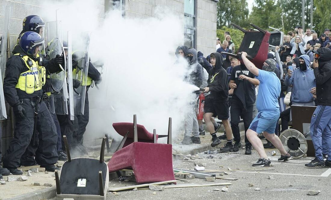 Un manifestante usa un extintor contra agentes de policía mientras estallan problemas durante una protesta contra la inmigración. FOTO: AP