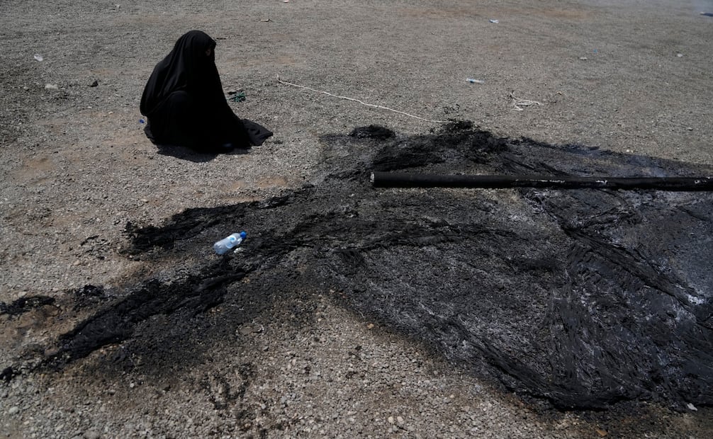 Una mujer participa en una ceremonia religiosa en Teherán junto a los restos calcinados de una tienda, durante la conmemoración del martirio del imán Hussein (25/05/2026). Foto: AP