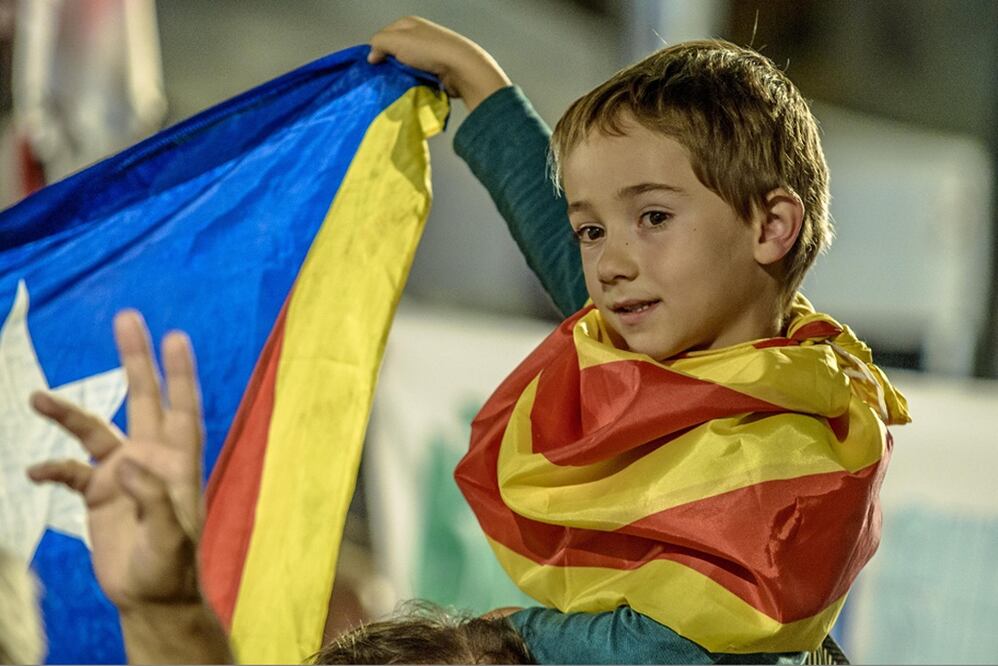Un simpatizante de los independentistas carga a un niño en sus hombros durante la fiesta de noche (XINHUA)