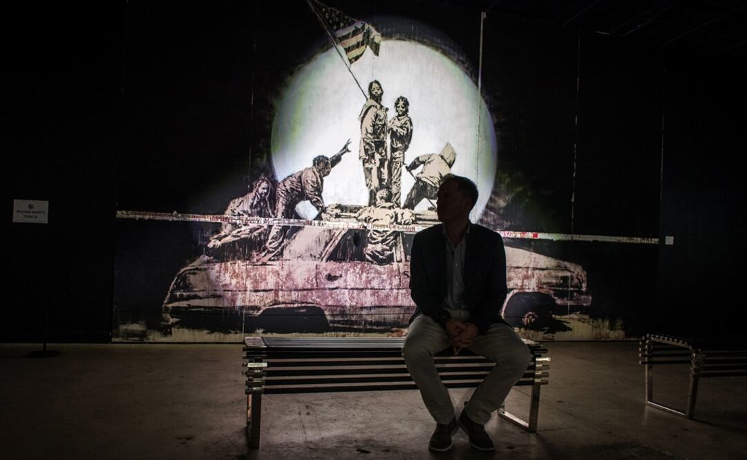 Una persona frente a la obra "Flag Wall" de Banksy durante una exposición en Miami. Foto: EFE/Giorgio Viera, archivo
