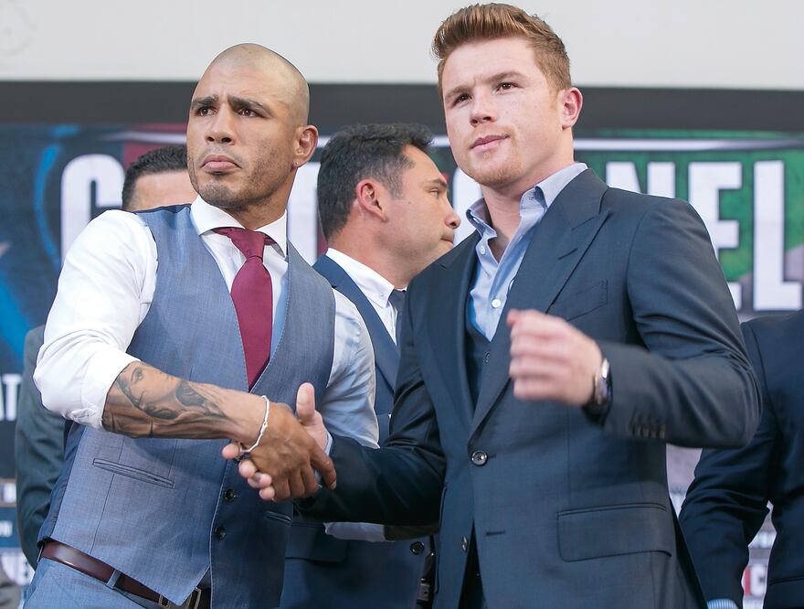 Los boxeadores Miguel Cotto y Saúl Álvarez se dieron la mano más por compromiso que por aprecio (DAMIAN DOVARGANES. AP)