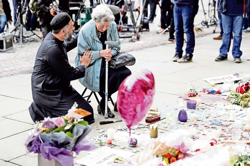 Sadiq Patel, musulmán, consuela a Renee Rachel Black, judía, junto a un memorial en homenaje a las víctimas del atentado (DARREN STAPLES. REUTERS)