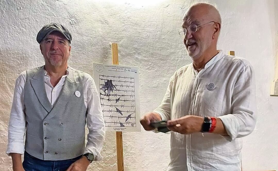 Ángel Boligán junto a un miembro del jurado y con el dibujo con el que obtuvo el segundo premio de la Bienal del Humor Luiz d’Oliveira Guimarães que se realiza en Coimbra, Portugal. Foto: Especial
