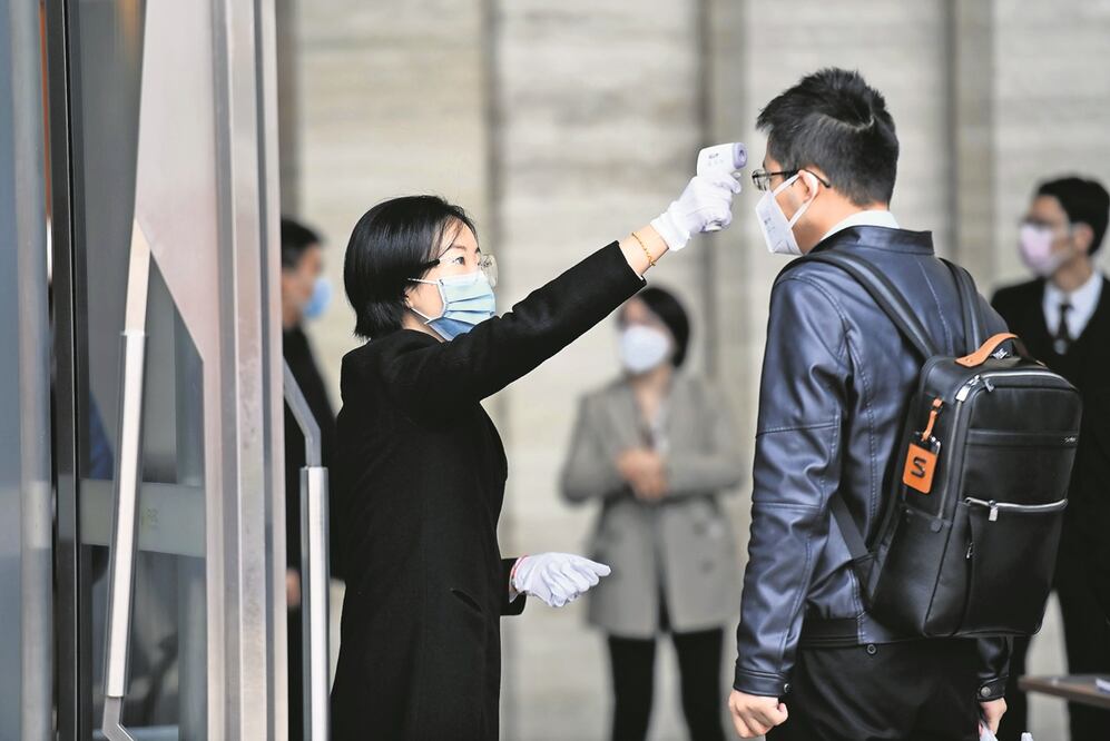 Una trabajadora mide la temperatura corporal para ingresar al Centro Internacional de Finanzas de Ping'an. Foto: El Universal 