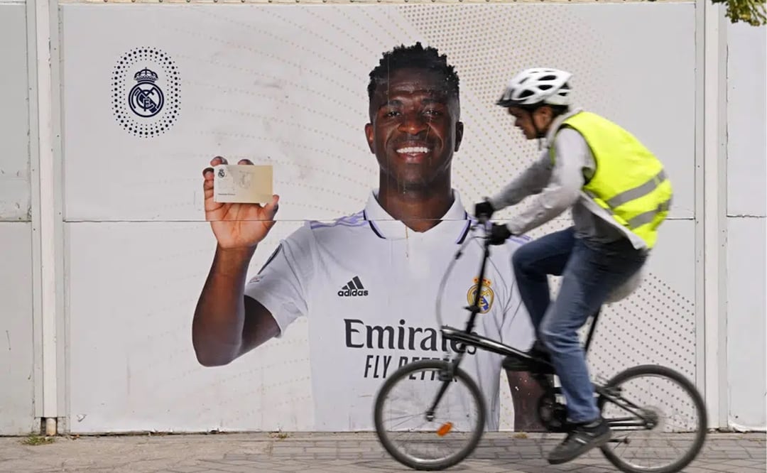 Un ciclista pasa frente a un afiche de Vinicius Junior, el delantero brasileño del Real Madrid, frente al estadio Santiago Bernábeu. Foto: AP