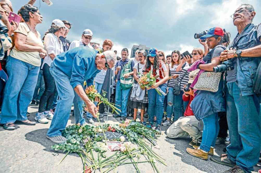 Venezolanos colocan flores luego de una misa por Miguel Castillo, quien murió tras ser herido con un arma de fuego en las protestas del miércoles en Caracas. (JUAN BARRETO. AFP)