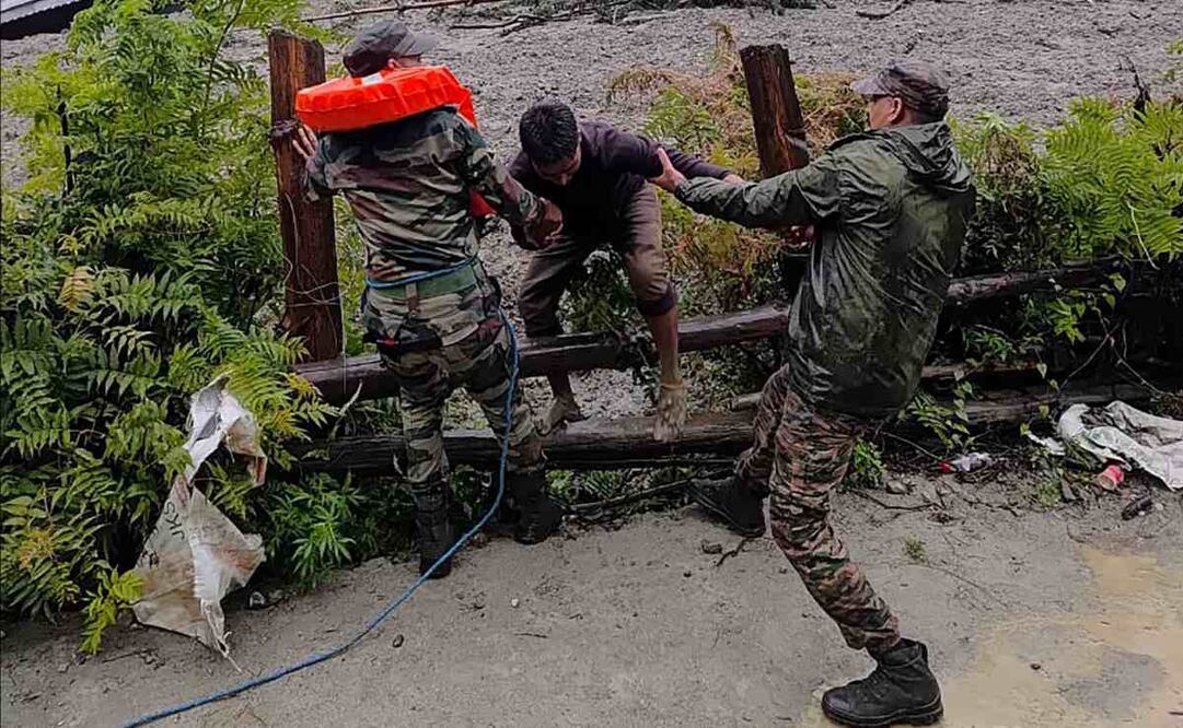 Esta fotografía, tomada el 5 de agosto de 2025 y difundida por el Ejército de la India, muestra a personal de seguridad rescatando a un residente local (C) de un denso lodo durante una operación de búsqueda y rescate tras un aguacero que causó un enorme deslizamiento de tierra en el estado indio de Uttarakhand. Una inundación repentina, que desató un torrente de lodo, azotó una localidad de la región del Himalaya el 5 de agosto, arrasando un valle montañoso antes de demoler edificios y causar la muerte de al menos cuatro personas. Foto: AFP